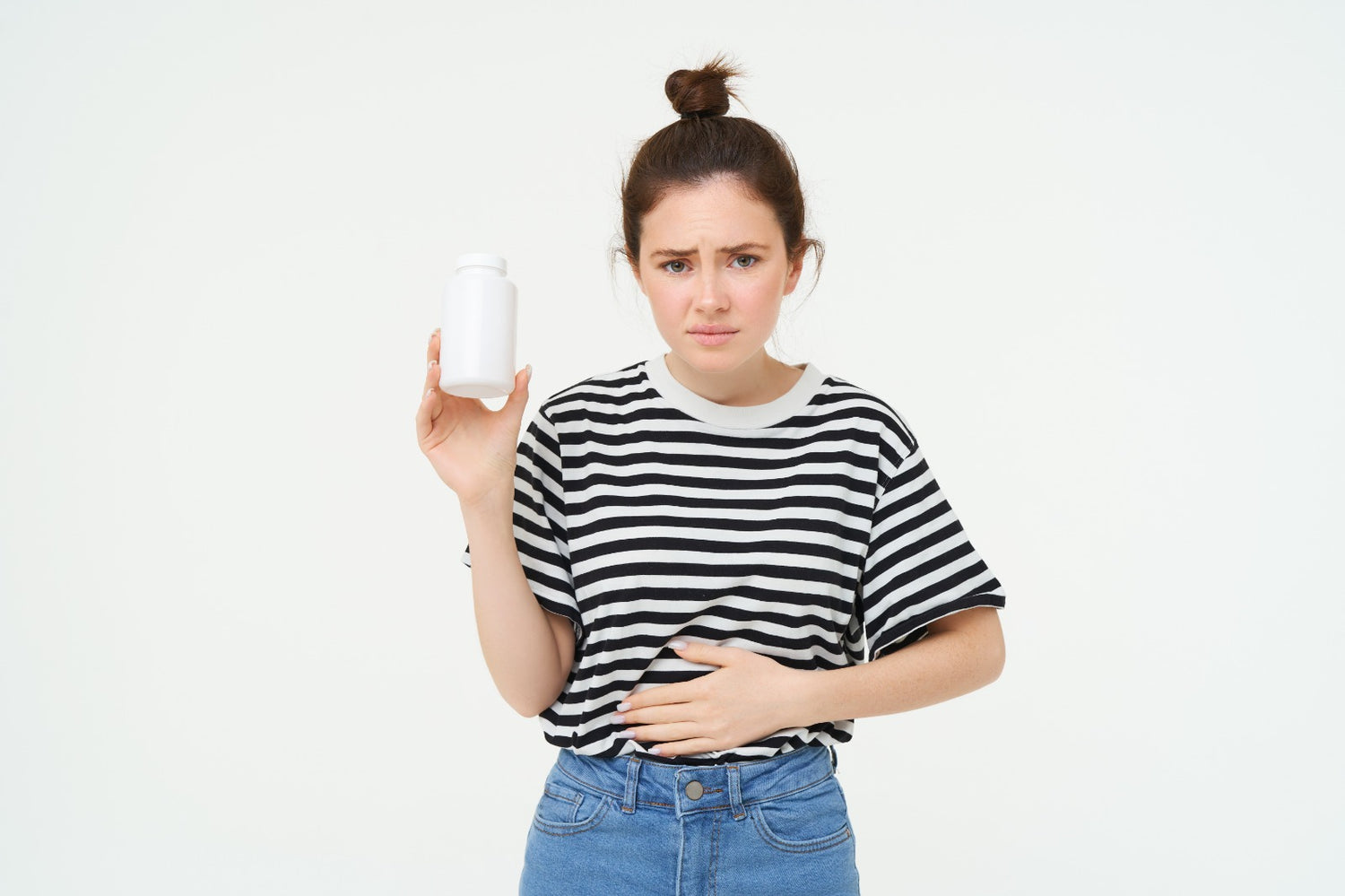 woman suffering from stomach ache holding medicine bottle