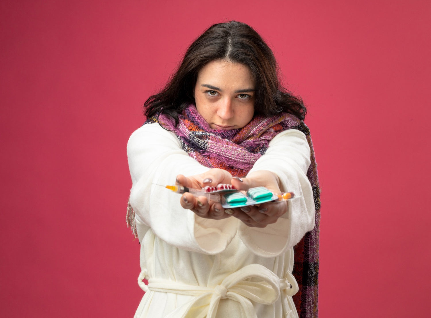 girl wearing robe holding pillow stretching out medical capsules towards background